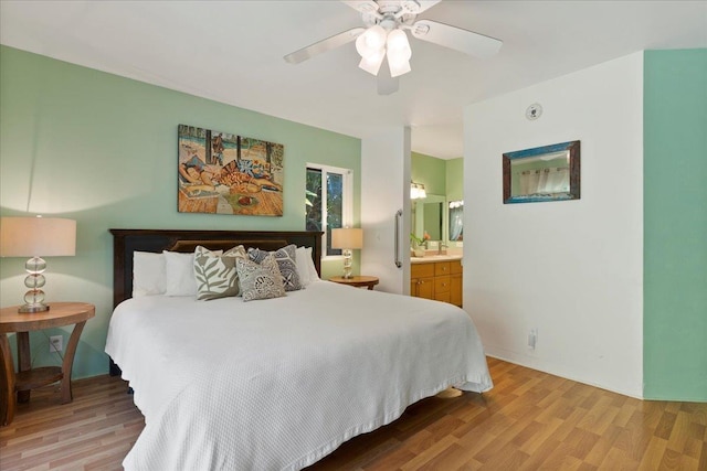 bedroom with ceiling fan, connected bathroom, and light hardwood / wood-style flooring