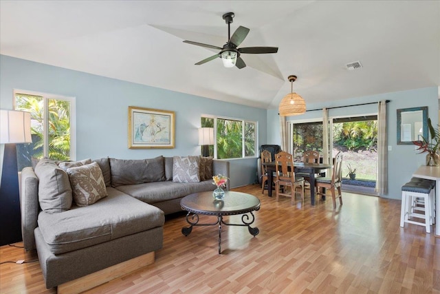 living room with vaulted ceiling, a wealth of natural light, and light hardwood / wood-style floors