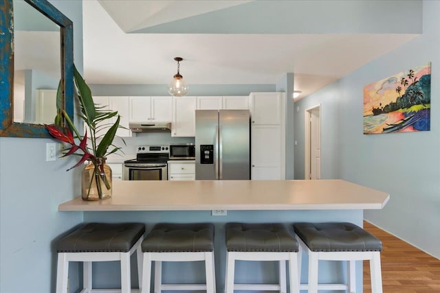 kitchen with white cabinets, appliances with stainless steel finishes, light hardwood / wood-style floors, a kitchen breakfast bar, and kitchen peninsula