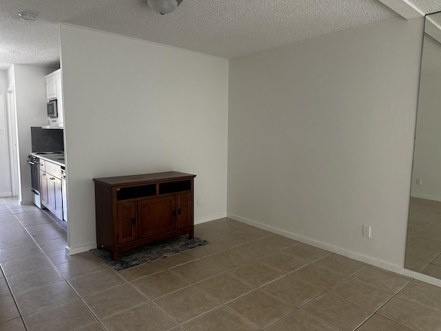 715 S Kihei Rd Unit D143, Kihei, HI 96753 - empty room with dark tile patterned floors, a textured ceiling, and baseboards