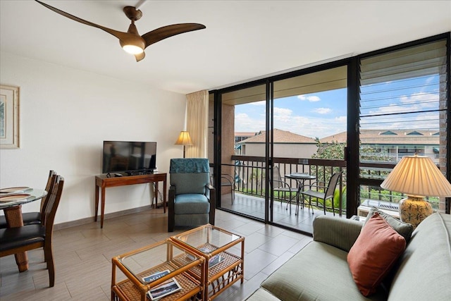 living room featuring a wall of windows, a ceiling fan, and baseboards