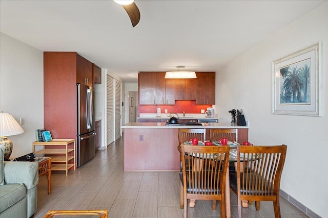 kitchen featuring freestanding refrigerator, a peninsula, light countertops, open floor plan, and light wood finished floors