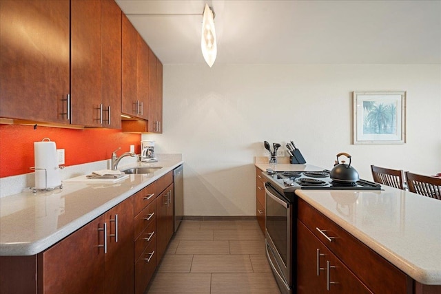 kitchen with appliances with stainless steel finishes, a sink, light countertops, baseboards, and a peninsula