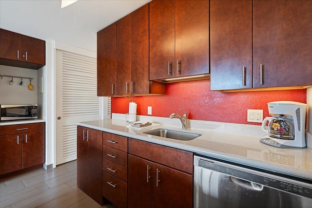 kitchen with stainless steel appliances, a sink, wood finished floors, and light stone counters