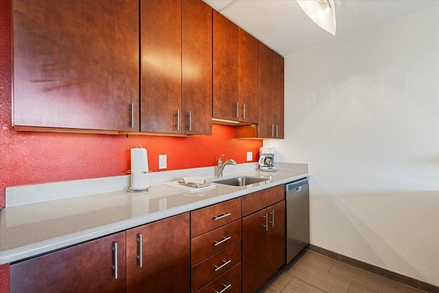 kitchen with stainless steel dishwasher, a sink, light countertops, and baseboards