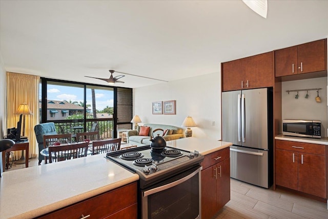 kitchen with appliances with stainless steel finishes, a wall of windows, light countertops, a ceiling fan, and open floor plan