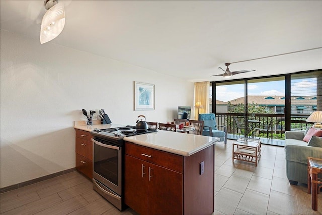 kitchen featuring stainless steel stove, open floor plan, floor to ceiling windows, light countertops, and ceiling fan