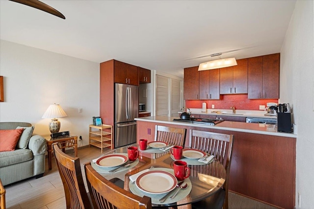 kitchen with stainless steel appliances, light wood-style flooring, open floor plan, a peninsula, and a sink