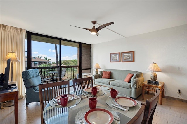 dining room with ceiling fan, a wall of windows, and baseboards