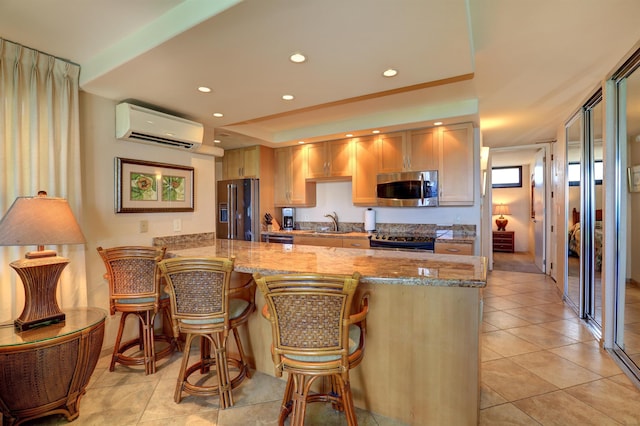 kitchen featuring a sink, an AC wall unit, a peninsula, stainless steel appliances, and light tile patterned flooring