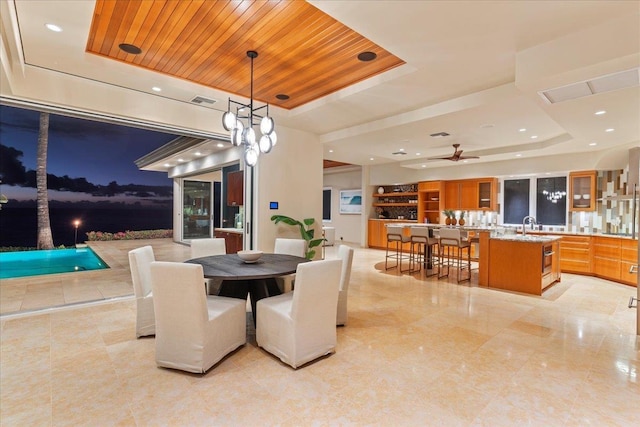 dining area with wood ceiling, a raised ceiling, ceiling fan, and sink