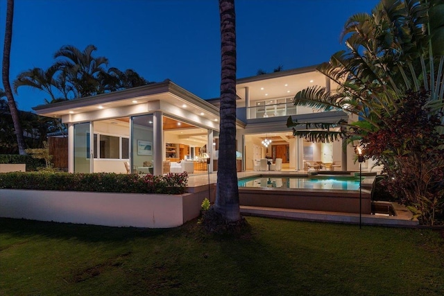 back house at night with a yard and a balcony