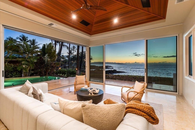 sunroom featuring a water view, a raised ceiling, ceiling fan, and wooden ceiling