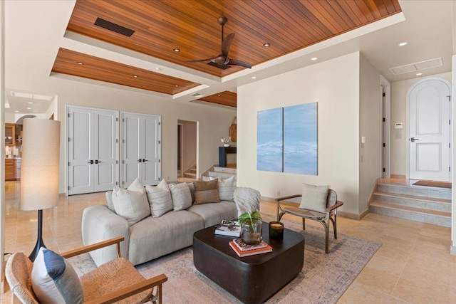 tiled living room with a raised ceiling, ceiling fan, and wooden ceiling