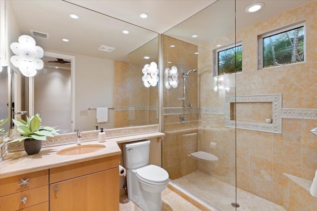 bathroom with tiled shower, vanity, and toilet