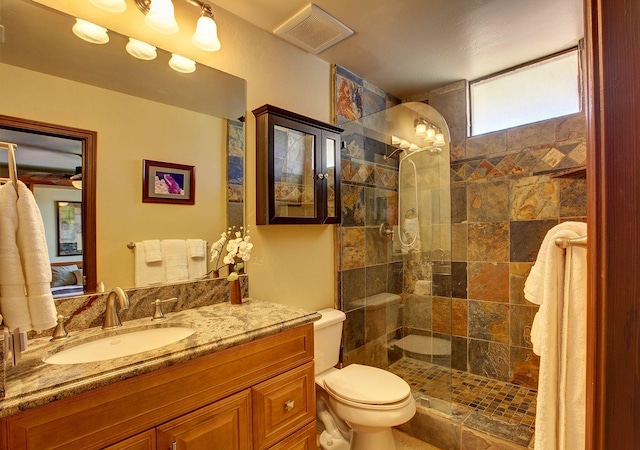 bathroom with a tile shower, vanity, and toilet