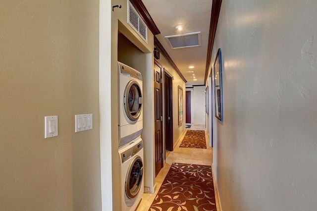 laundry room with tile patterned floors, stacked washer / drying machine, and ornamental molding