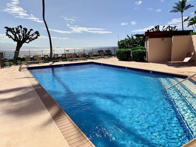 view of swimming pool featuring a water view and a patio area