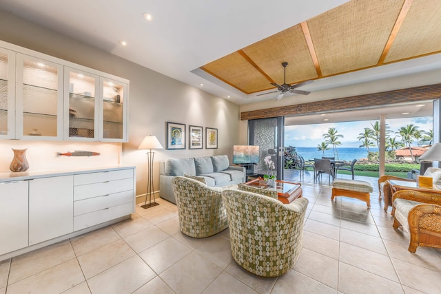 tiled living room featuring ceiling fan, wood ceiling, and a water view