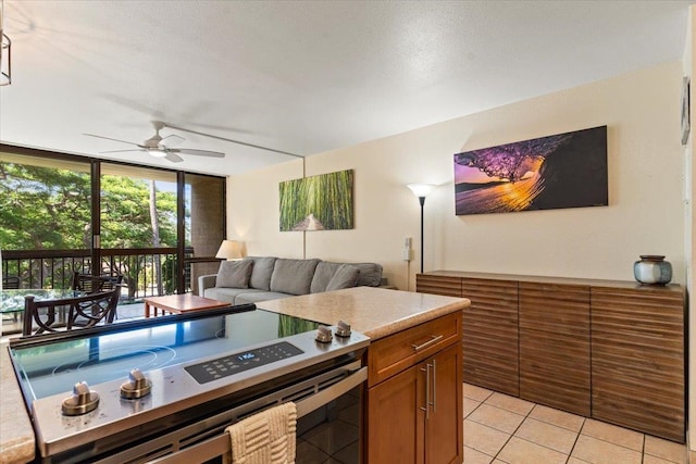 kitchen featuring stainless steel stove, ceiling fan, light tile patterned floors, a textured ceiling, and floor to ceiling windows