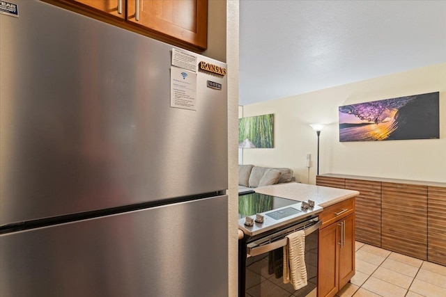 kitchen featuring appliances with stainless steel finishes, light stone counters, and light tile patterned floors