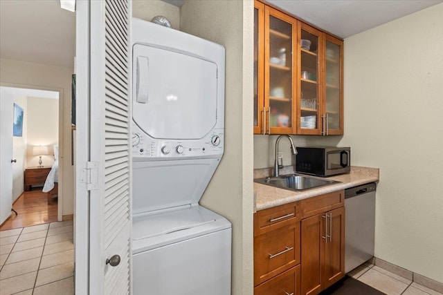 washroom with stacked washer and dryer, sink, and light tile patterned floors