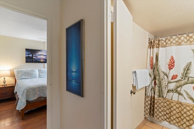 bathroom with a textured ceiling, walk in shower, and wood-type flooring