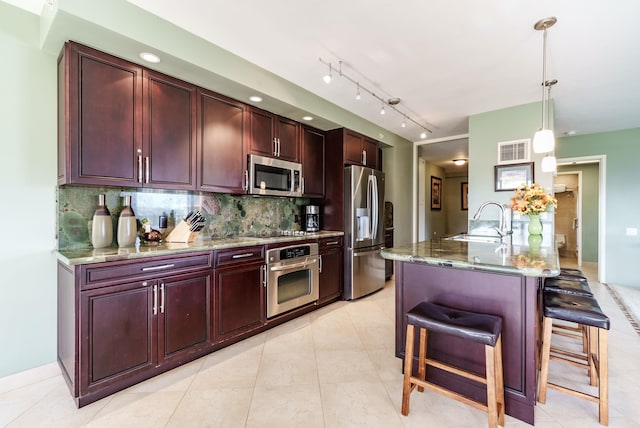 kitchen with decorative light fixtures, dark stone counters, a breakfast bar, appliances with stainless steel finishes, and sink