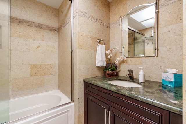 bathroom with tiled shower / bath, tile walls, and vanity