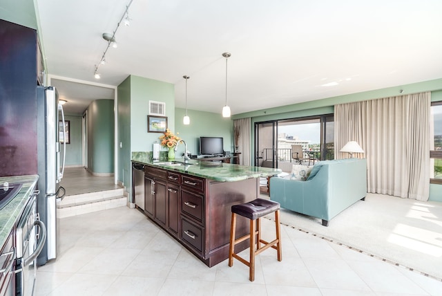 kitchen featuring light stone counters, a kitchen bar, sink, track lighting, and hanging light fixtures