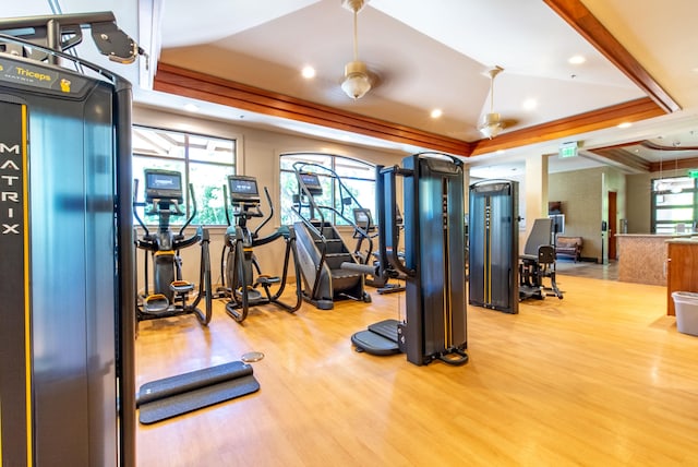 exercise room with ornamental molding, a tray ceiling, and light hardwood / wood-style floors