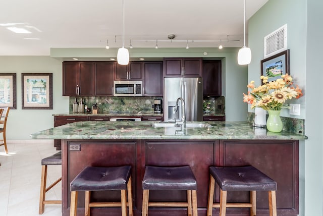 kitchen with hanging light fixtures, tasteful backsplash, light stone counters, and stainless steel appliances