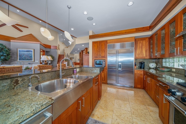 kitchen with stone countertops, decorative backsplash, stainless steel appliances, and hanging light fixtures