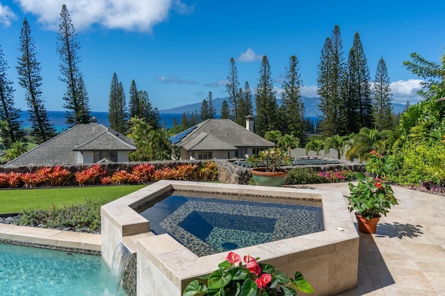 view of pool featuring pool water feature, a mountain view, and an in ground hot tub