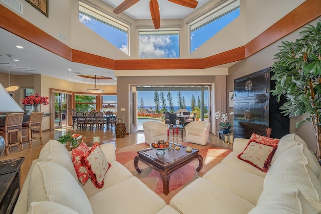 living room with ceiling fan, light tile patterned floors, and a high ceiling