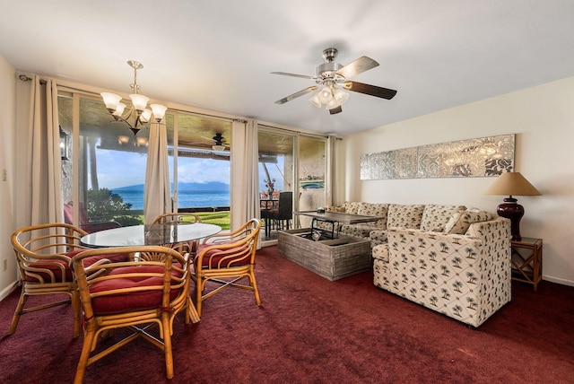 dining room featuring a water view, dark colored carpet, and ceiling fan with notable chandelier