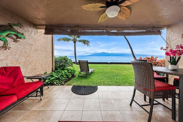 view of patio with a water and mountain view and ceiling fan