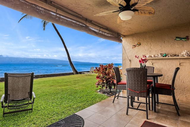 view of patio with a water view and ceiling fan