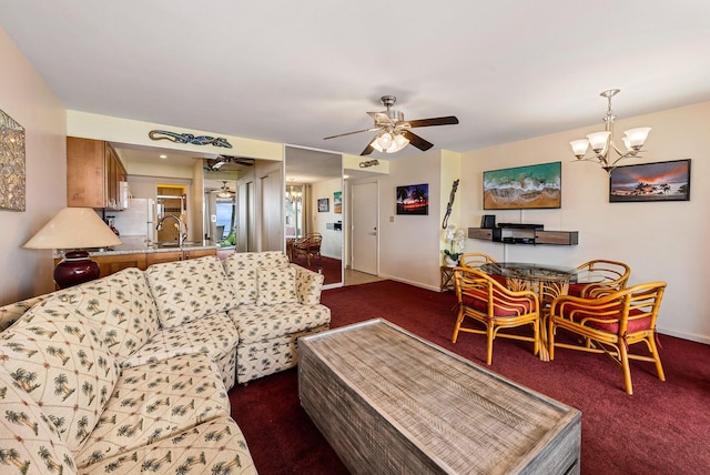 living room with dark carpet, sink, and ceiling fan with notable chandelier