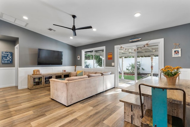 living room with ceiling fan, light hardwood / wood-style flooring, and vaulted ceiling