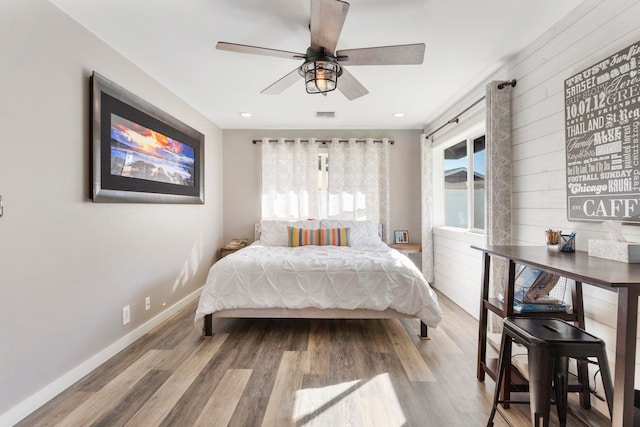 bedroom with wood-type flooring, wood walls, and ceiling fan