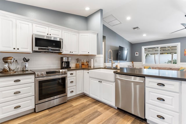 kitchen with light wood-type flooring, tasteful backsplash, sink, white cabinetry, and appliances with stainless steel finishes