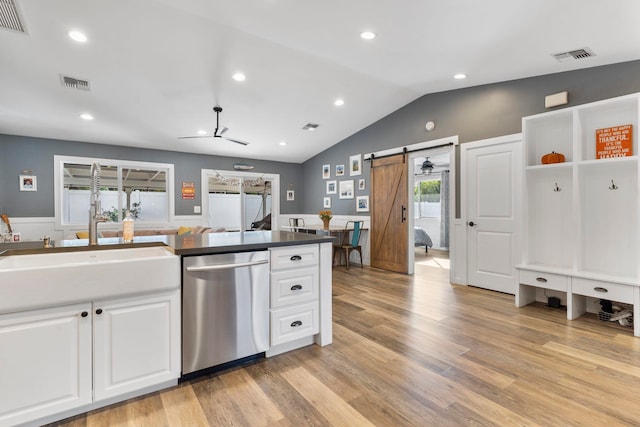 kitchen featuring white cabinets, light hardwood / wood-style flooring, a barn door, and stainless steel dishwasher