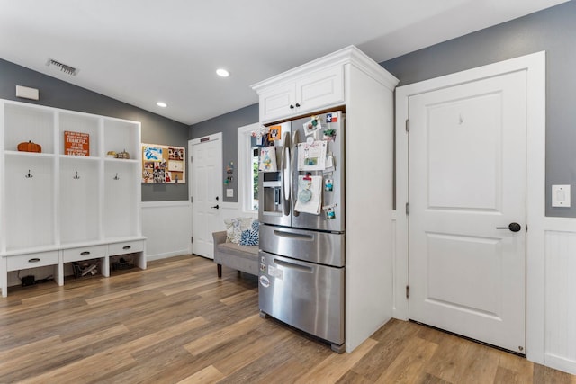 kitchen featuring white cabinets, stainless steel refrigerator with ice dispenser, hardwood / wood-style floors, and vaulted ceiling