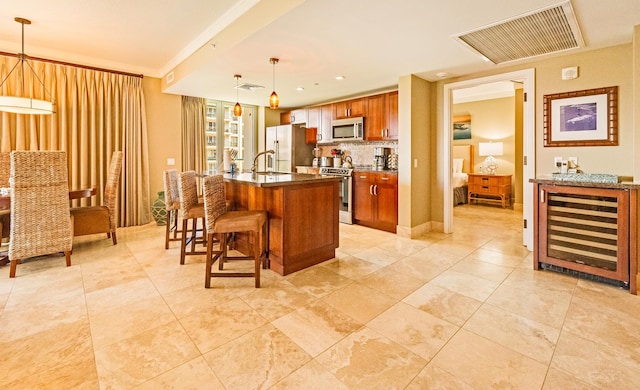 kitchen with light tile patterned flooring, stainless steel appliances, an island with sink, and wine cooler