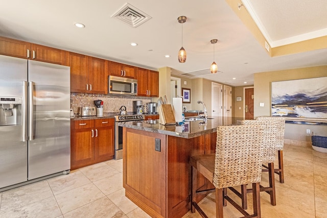 kitchen with appliances with stainless steel finishes, decorative backsplash, a kitchen island with sink, a kitchen breakfast bar, and light tile patterned flooring