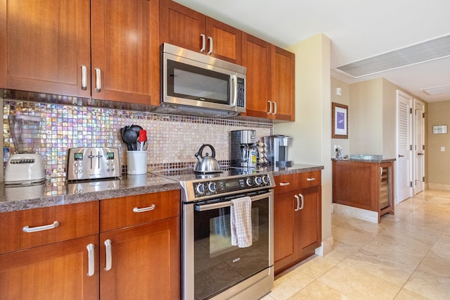 kitchen with dark stone countertops, decorative backsplash, stainless steel appliances, and light tile patterned floors