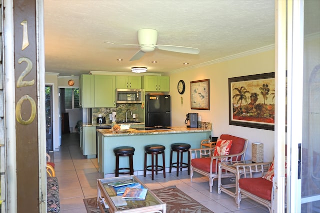 kitchen featuring green cabinetry, kitchen peninsula, ceiling fan, a breakfast bar area, and black fridge