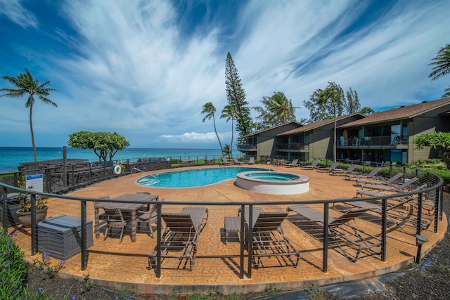 view of swimming pool featuring a water view, a patio area, and a hot tub