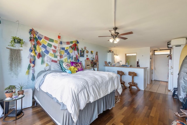 bedroom featuring a wall mounted AC, dark hardwood / wood-style floors, and ceiling fan